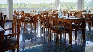 A restaurant with wooden tables and chairs, a polished floor, and large windows offering a view of the landscape.