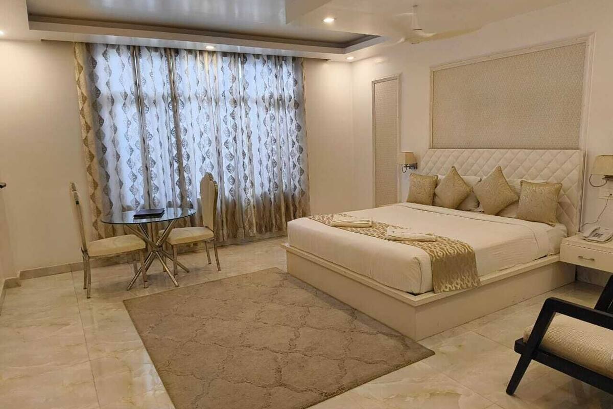 Une chambre moderne avec un grand lit, des tables de chevet, une petite table avec des chaises et un rideau à motifs.