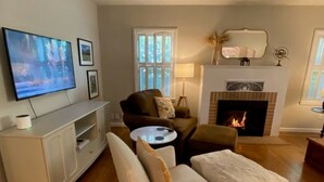 A living room with a flat-screen TV, a fireplace, and a sofa. - Mid-Century Modern Bungalow Near McKinley Park! (Sacramento)
