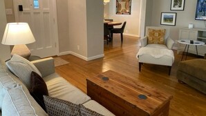 A living room with a wooden coffee table, a sofa, a chair, and a dining area with a table and chairs. - Mid-Century Modern Bungalow Near McKinley Park! (Sacramento)