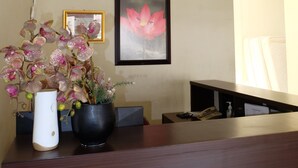 A reception desk with a vase of orchids, a framed certificate, and a clock on the wall. - De Nusantara Hotel Syariah (Medan)