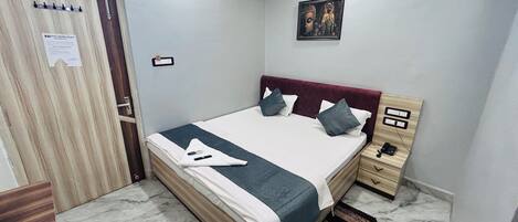 A neatly arranged bedroom with a bed, bedside table, and a wall-mounted picture.
