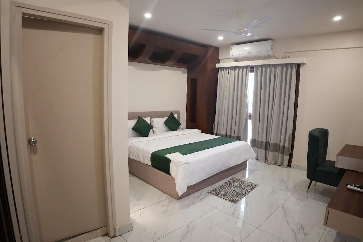 A hotel room with a bed, a desk, a chair, a ceiling fan, and an air conditioning unit.