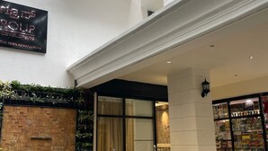 A hotel entrance with a staircase leading to a second floor, a sign for 'Indy Group Developers', and a storefront with various items on display. - AK CASTLE SUITES (Bengaluru)