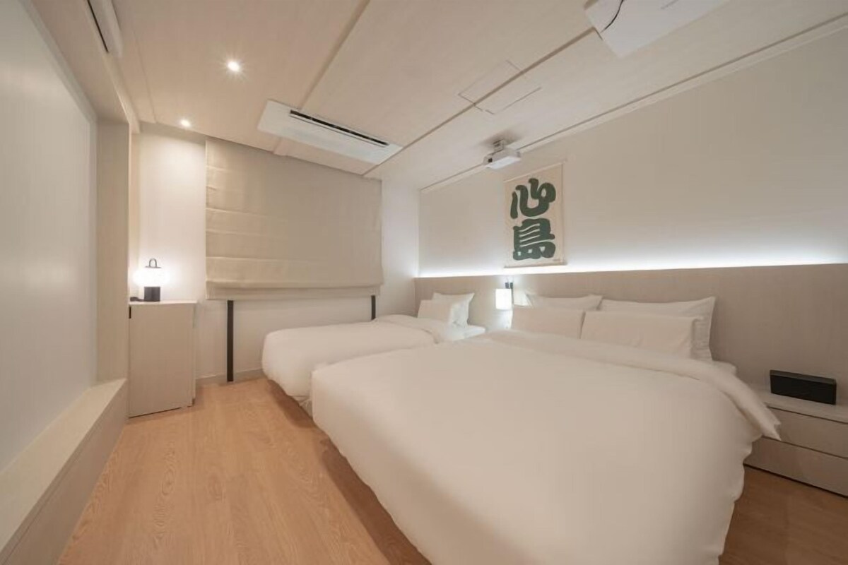 A modern hotel room with a large bed, bedside tables, and a wall-mounted air conditioning unit.