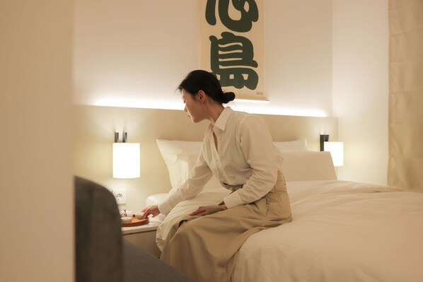 A hotel room with a bed, bedside table, lamp, and a wall with large text. - Simdo Hotel & Spa Sillim by Anook (Seoul)