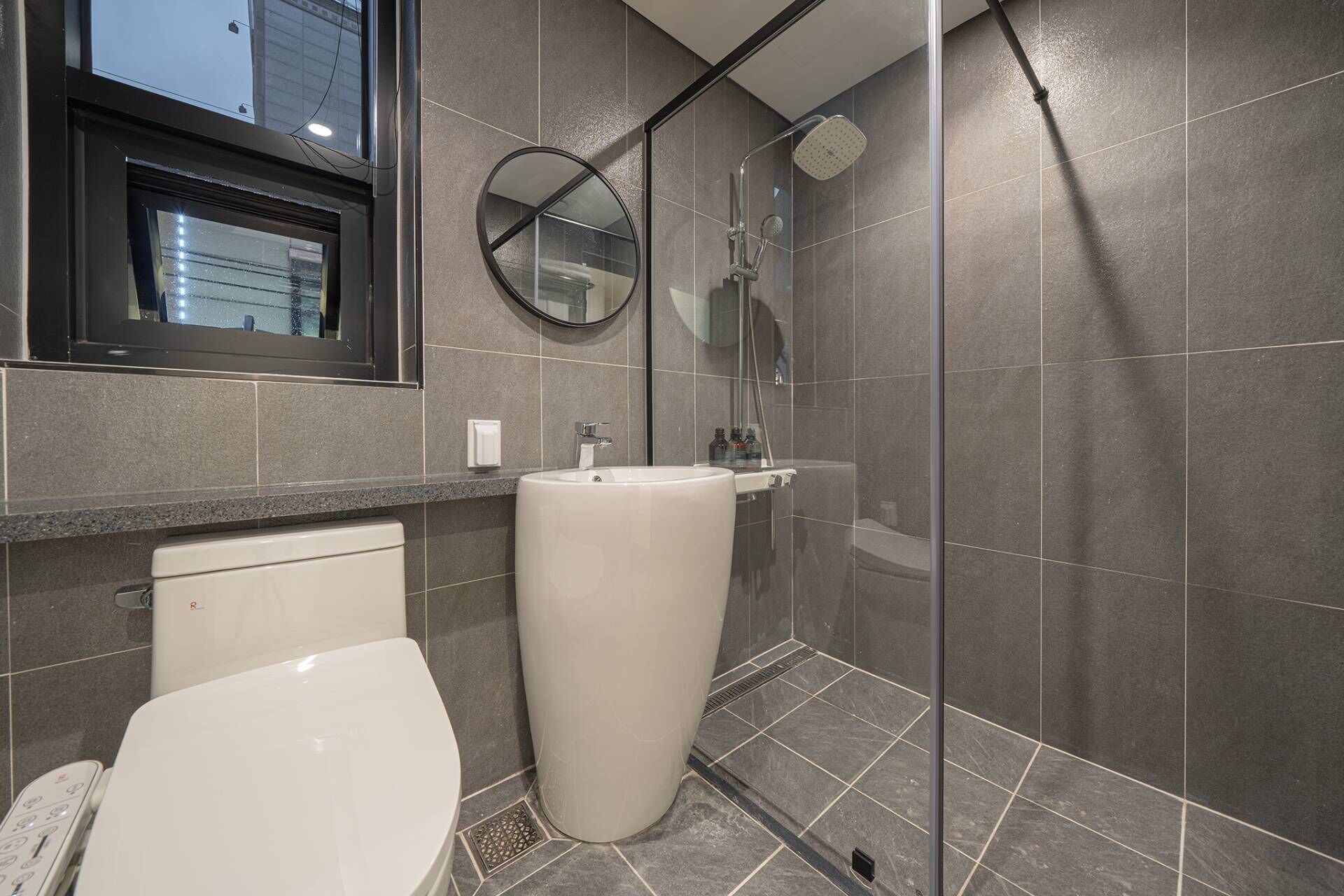 Une salle de bain moderne équipée de toilettes, d’un grand lavabo et d’une douche.