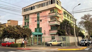 Un edificio a più piani con facciata rosa, dettagli verdi e tetto piatto.