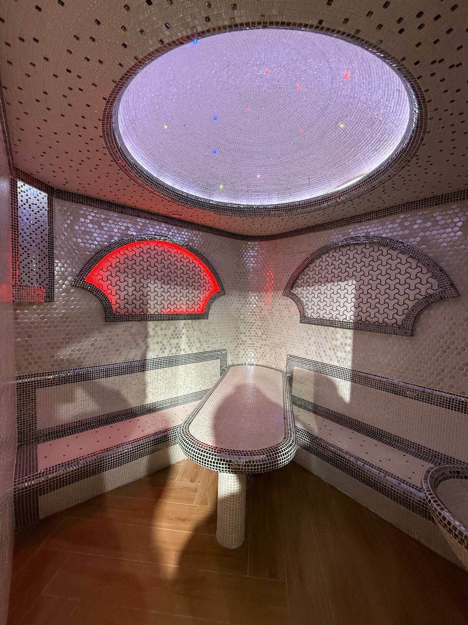A room with a round skylight, a dining table with chairs, and a patterned wall.