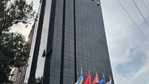 Un edificio alto e moderno con una facciata in vetro riflettente e un ingresso ben visibile.