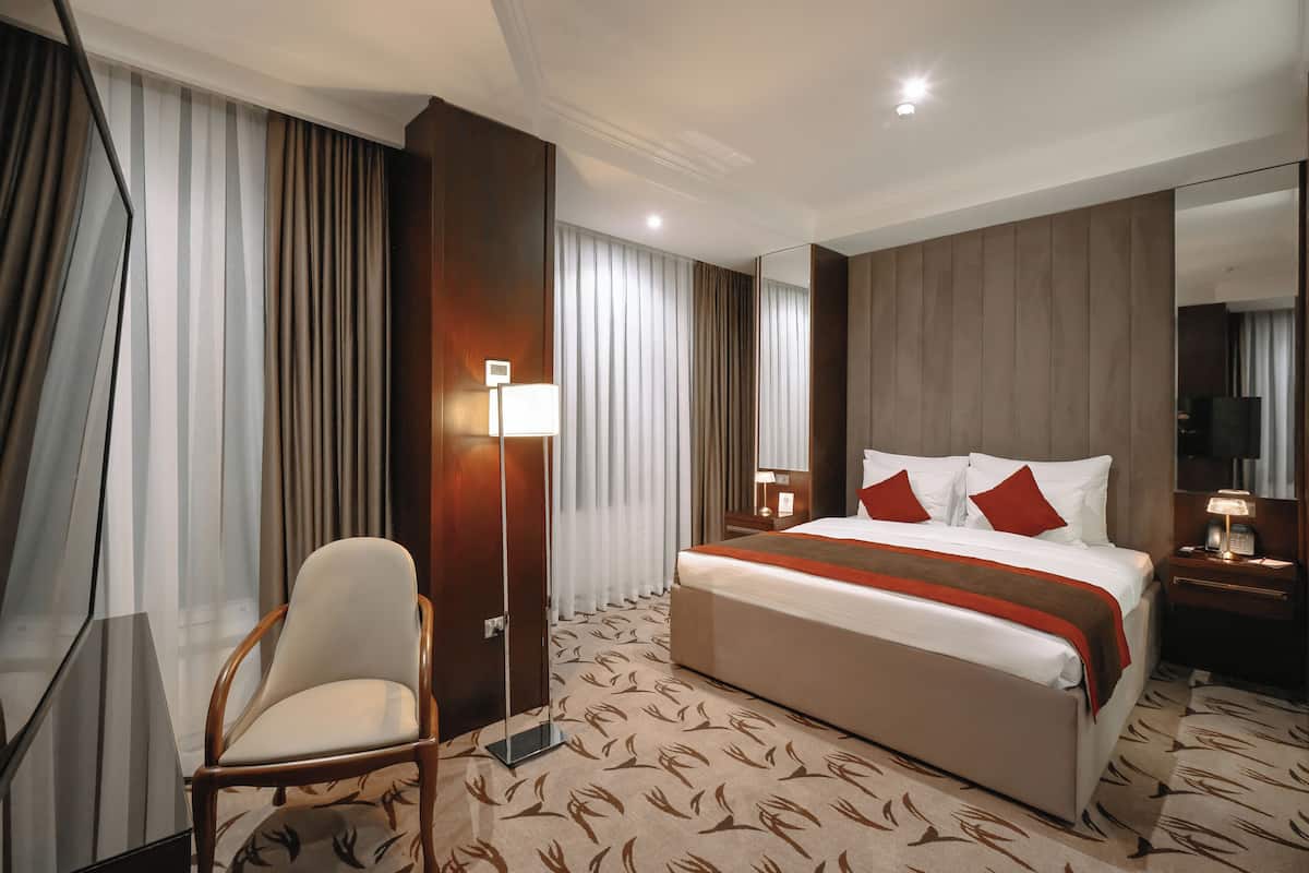 Une chambre d’hôtel avec un grand lit, une chaise, un bureau et un miroir.