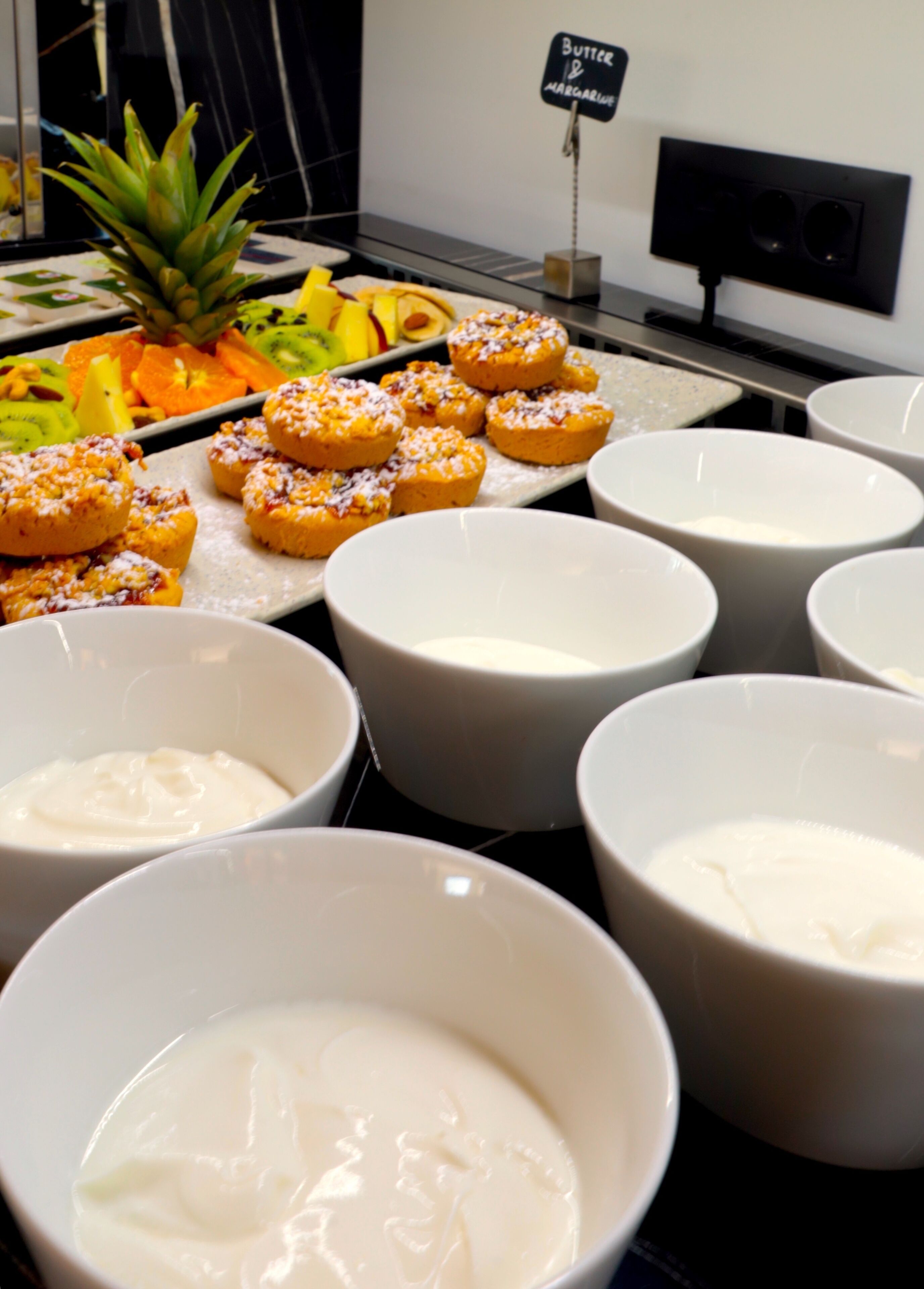 A buffet with various food items and bowls of white sauce.