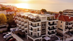 Un hotel de varios pisos con balcones, una terraza en la azotea y vistas al mar.