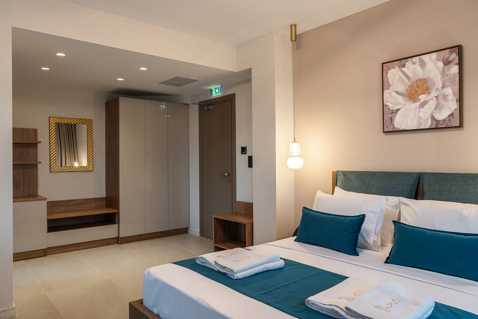 A hotel room with a bed, a nightstand, a mirror, and a painting on the wall.