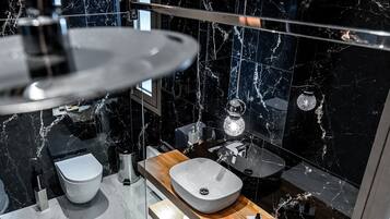 Un baño moderno con salpicadero de mármol, tocador de madera, lavabo sobre encimera y retrete.
