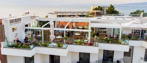 A rooftop bar and restaurant with outdoor seating, overlooking a body of water.