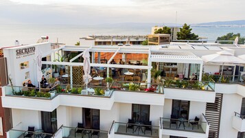 Bar y restaurante en la azotea con mesas al aire libre, con vistas a un cuerpo de agua.