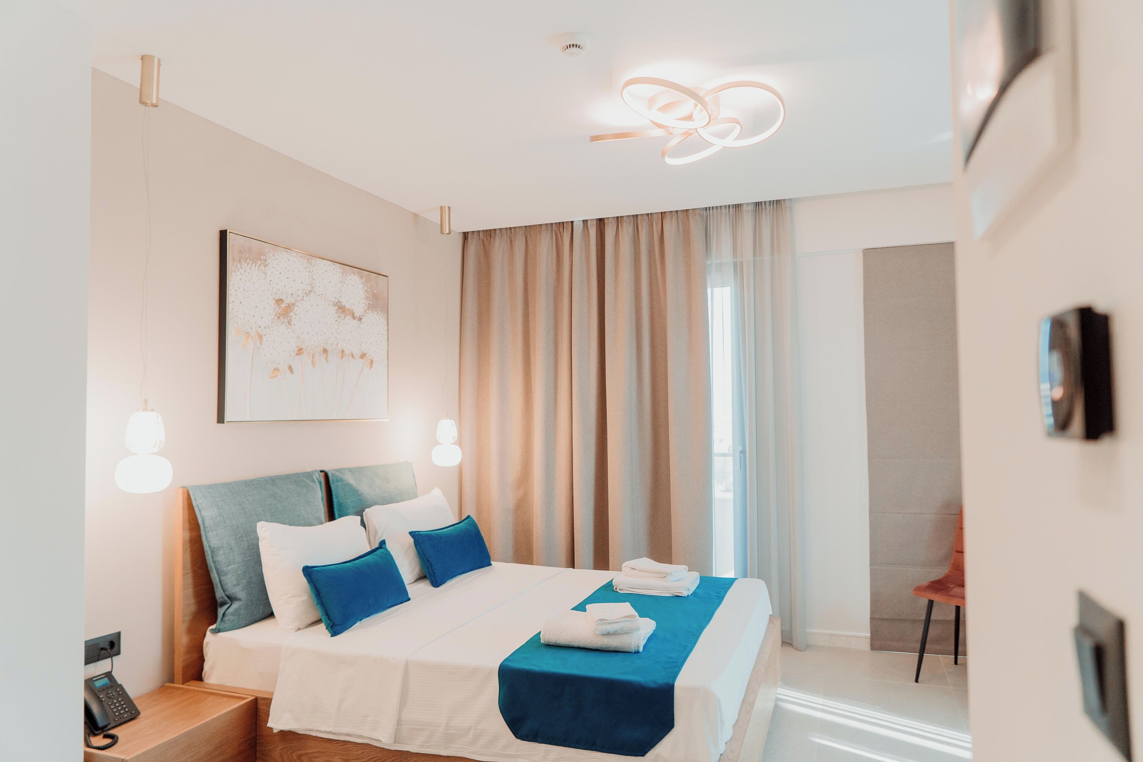 Une chambre d’hôtel moderne avec un lit bien fait, un téléphone sur la table de chevet et une grande fenêtre avec des rideaux.