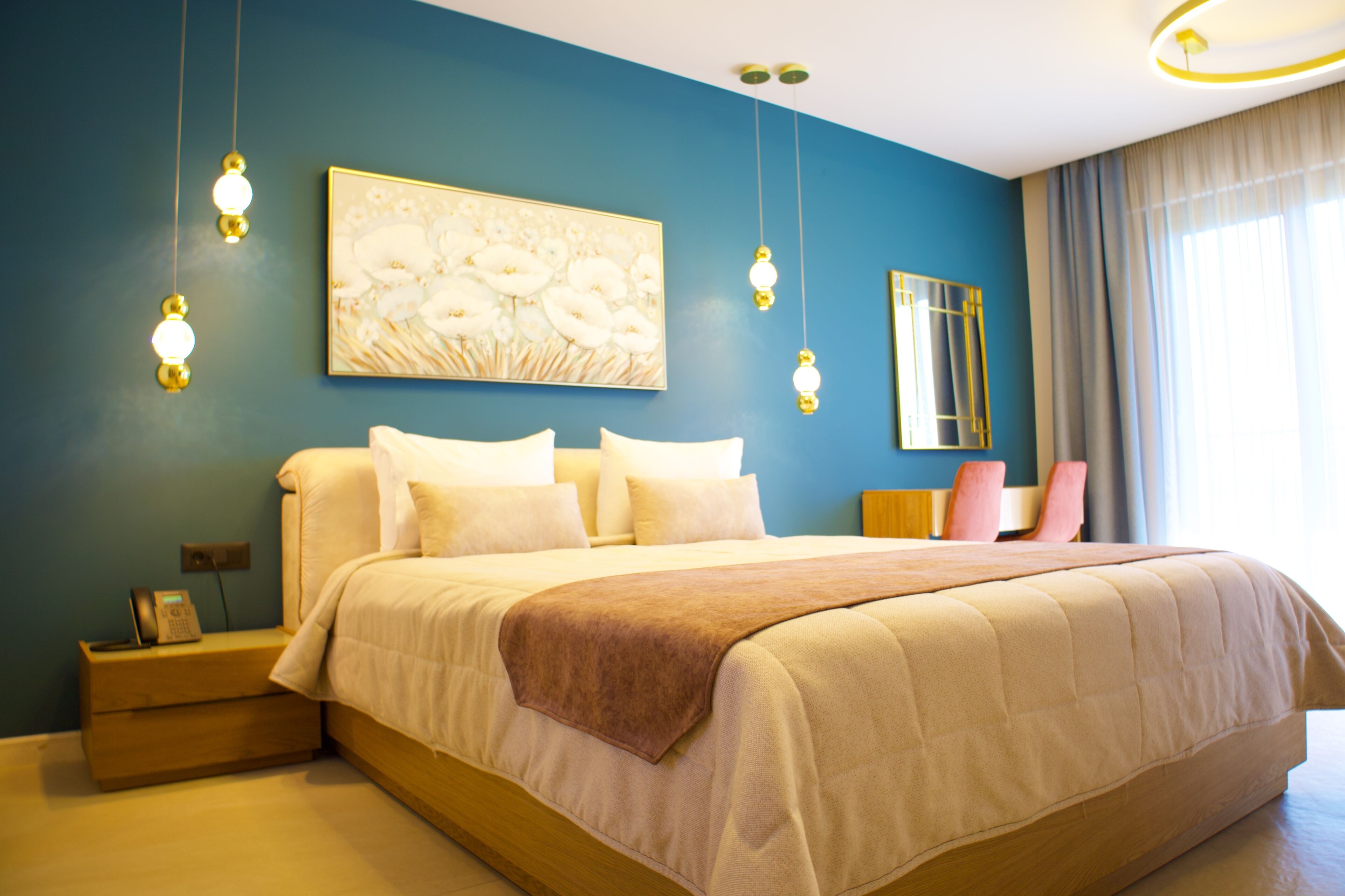A bedroom with a large bed, bedside tables, a nightstand, a painting, and a mirror.