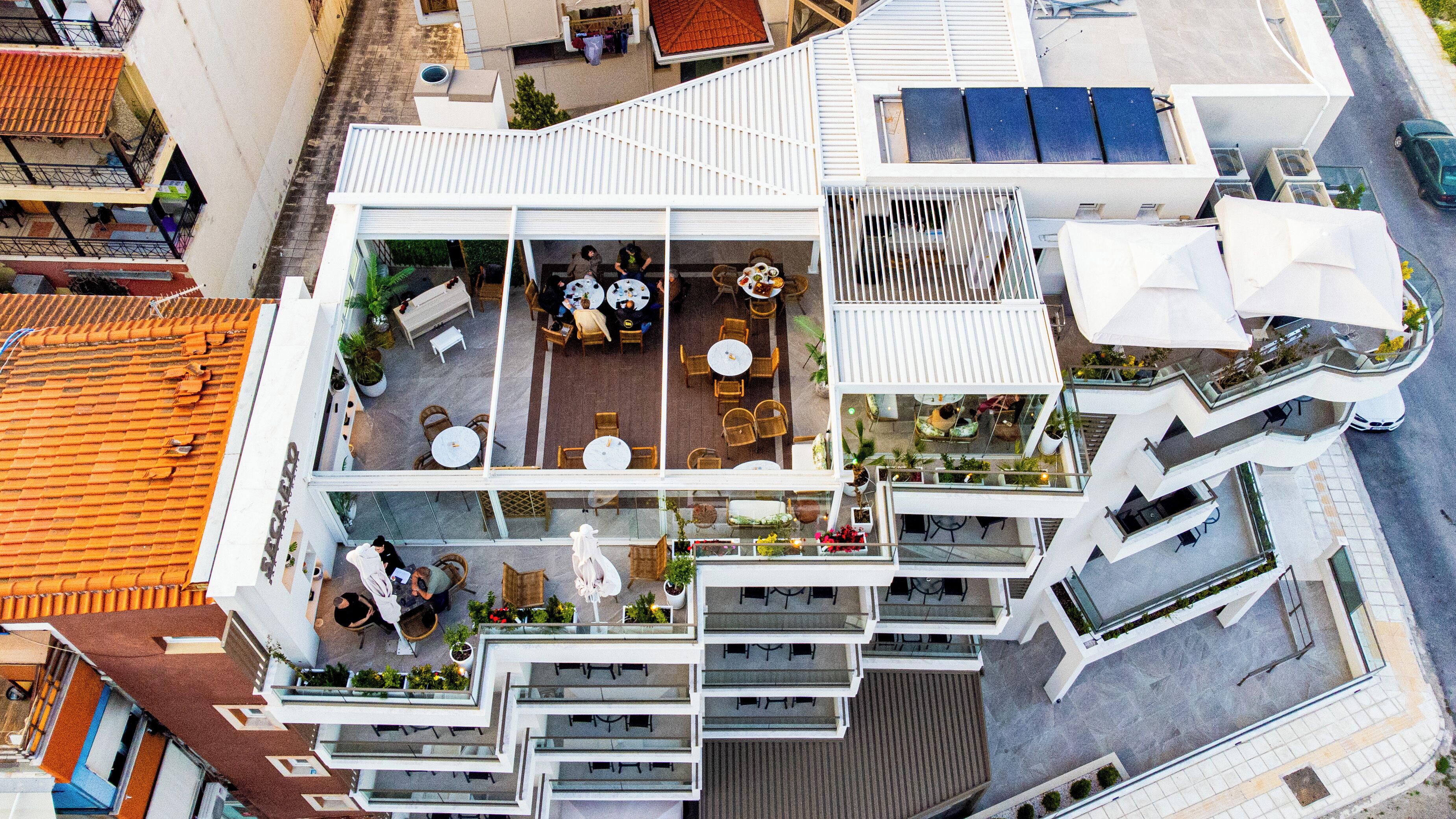 A modern hotel with multiple floors, outdoor seating areas, and a rooftop terrace.