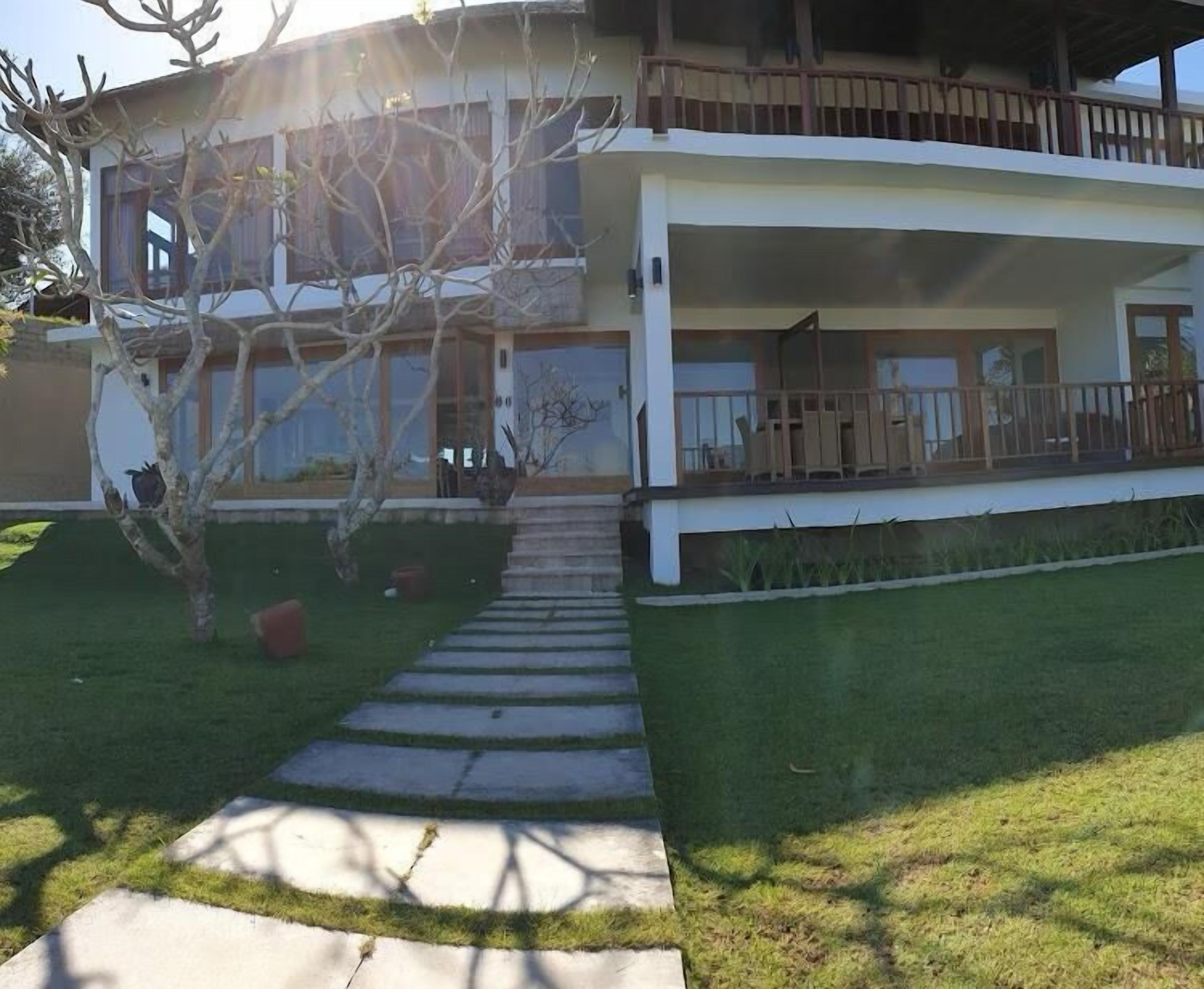 Una casa moderna de dos pisos con un porche cubierto y un camino de piedra que conduce a la entrada.