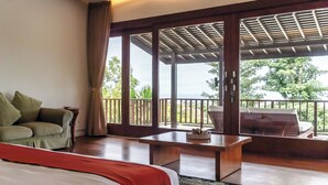 Une chambre avec un lit, un canapé, une table et un balcon donnant sur des arbres.