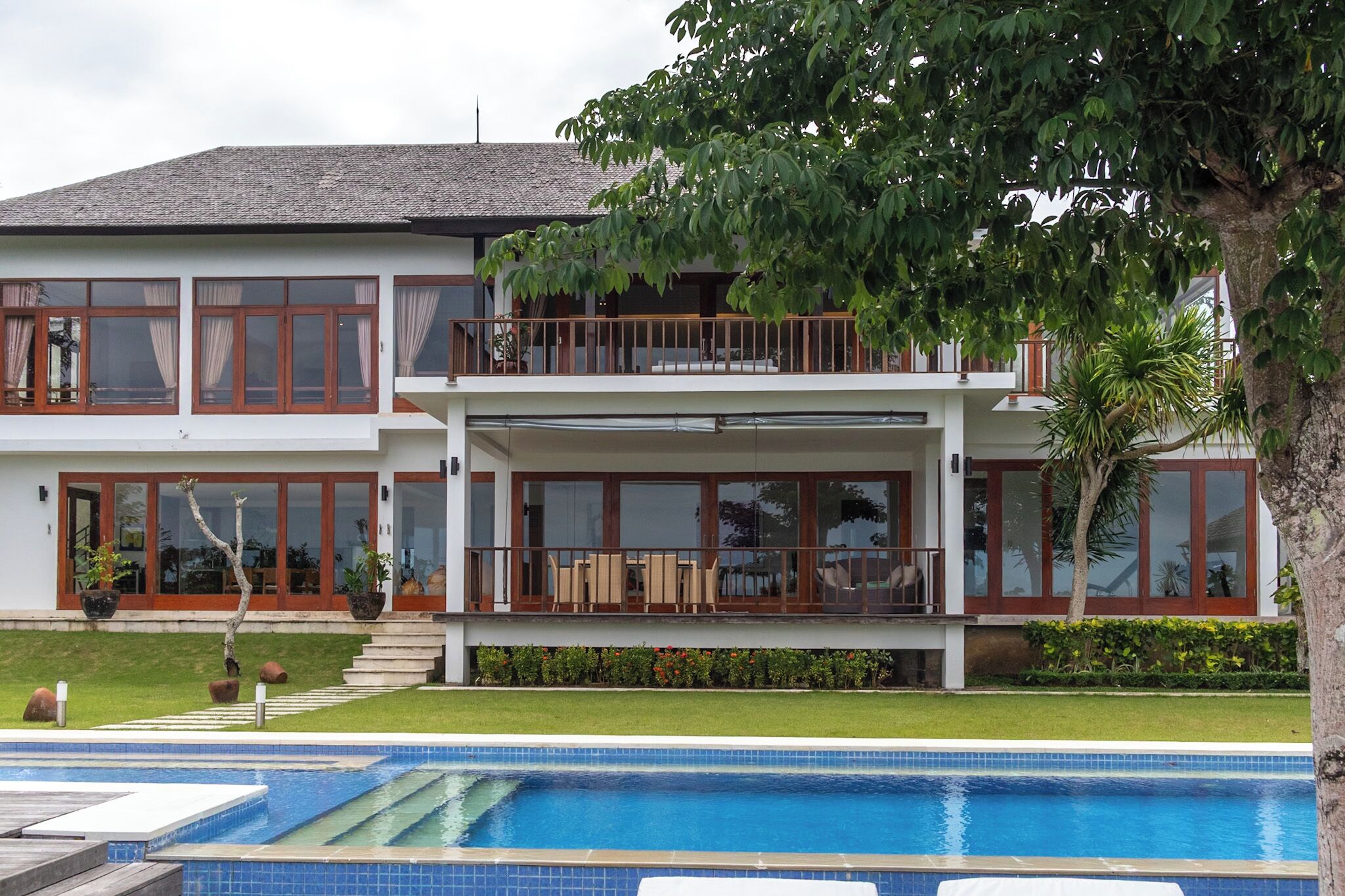 A two-story house with a swimming pool in the foreground.
