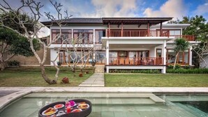 Une maison moderne à deux étages, avec une piscine en premier plan.