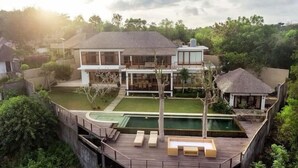 Une maison moderne dotée d’une grande terrasse, d’une piscine et d’un jardin bien entretenu.