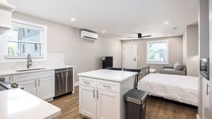 Una cocina compacta y moderna con armarios blancos, lavavajillas y un pequeño comedor.