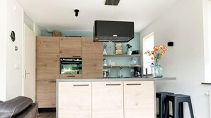Una cocina moderna con gabinetes de madera, horno integrado y extractor de aire negro.
