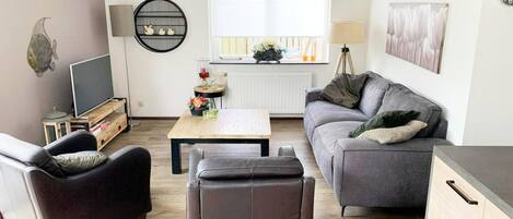 A living room with a sofa, a coffee table, a TV, and a lamp.