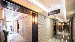 A modern hotel corridor with a polished marble floor, wooden paneling on the walls, and a sign indicating the hotel name. - Hotel Bom (Pohang)