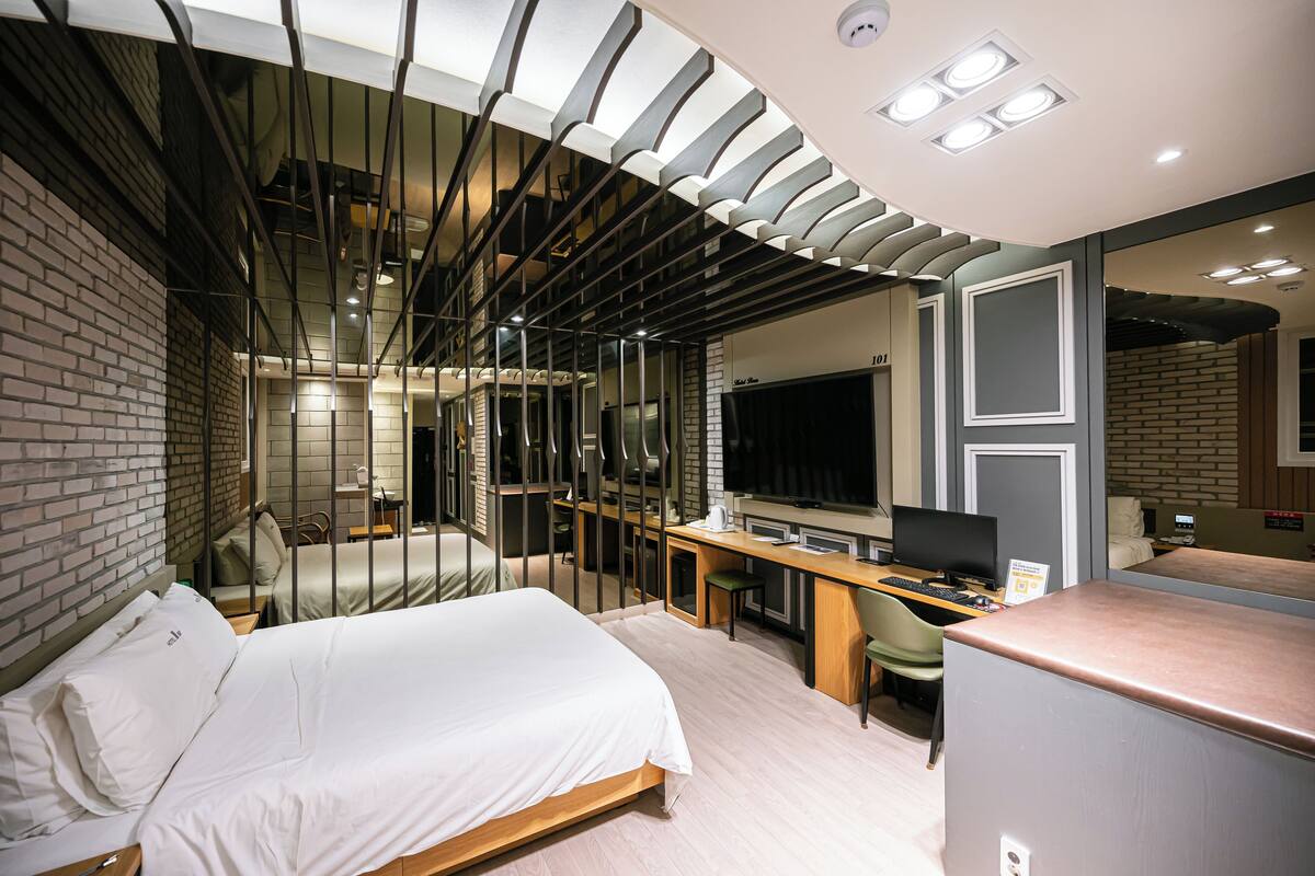 A modern hotel room with a bed, desk, and seating area.