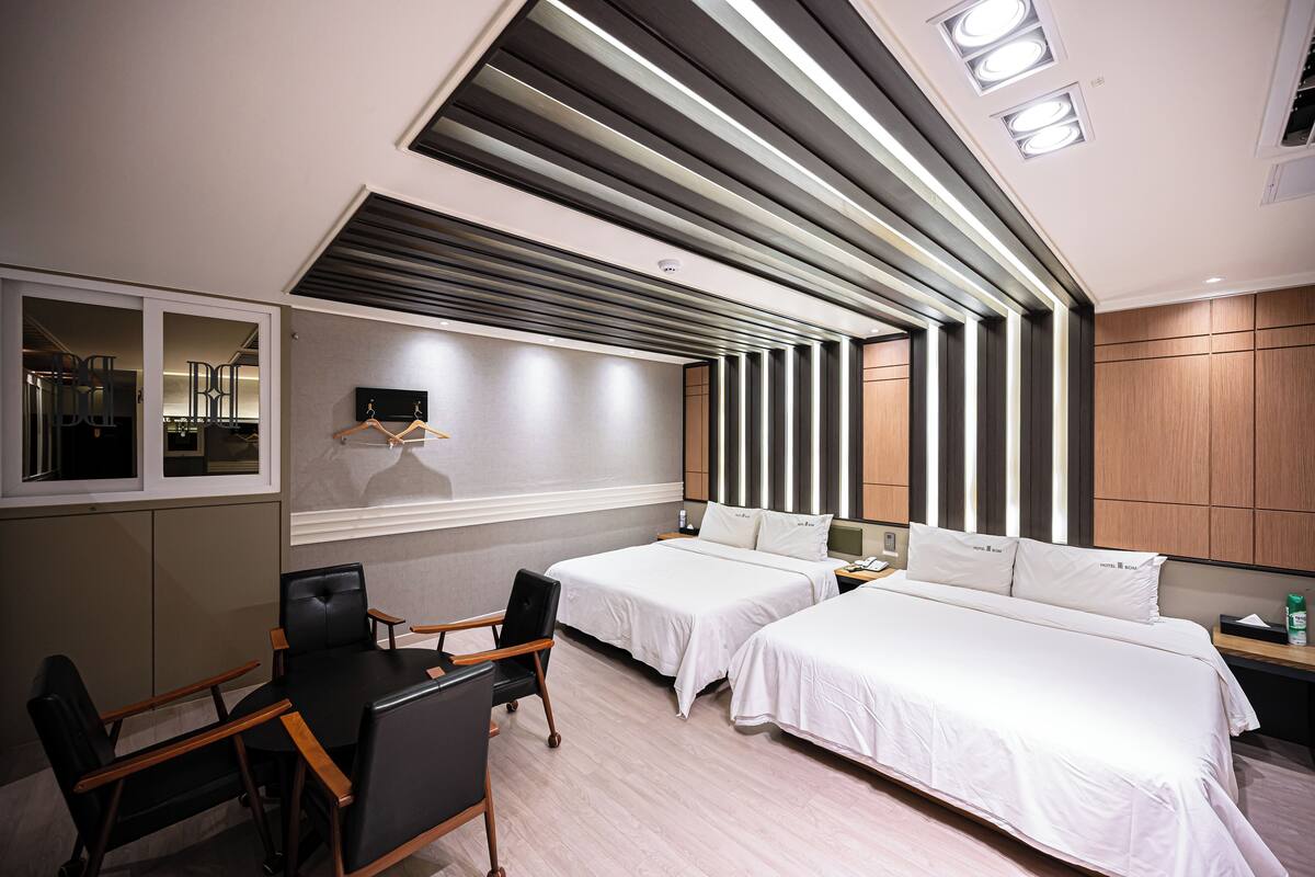 A hotel room with two beds, a desk, and a chair.
