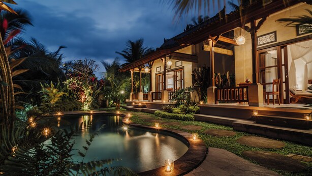 A pool surrounded by tropical plants and a building with a covered patio. - Ancut Sari Private Villa (Ubud)