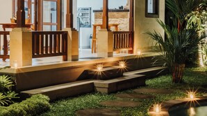 A house with a covered porch, steps leading to the entrance, and a pool area with lights. - Ancut Sari Private Villa (Ubud)