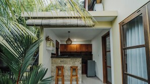 A compact kitchen with a central island, wooden stools, and a refrigerator. - Ancut Sari Private Villa (Ubud)