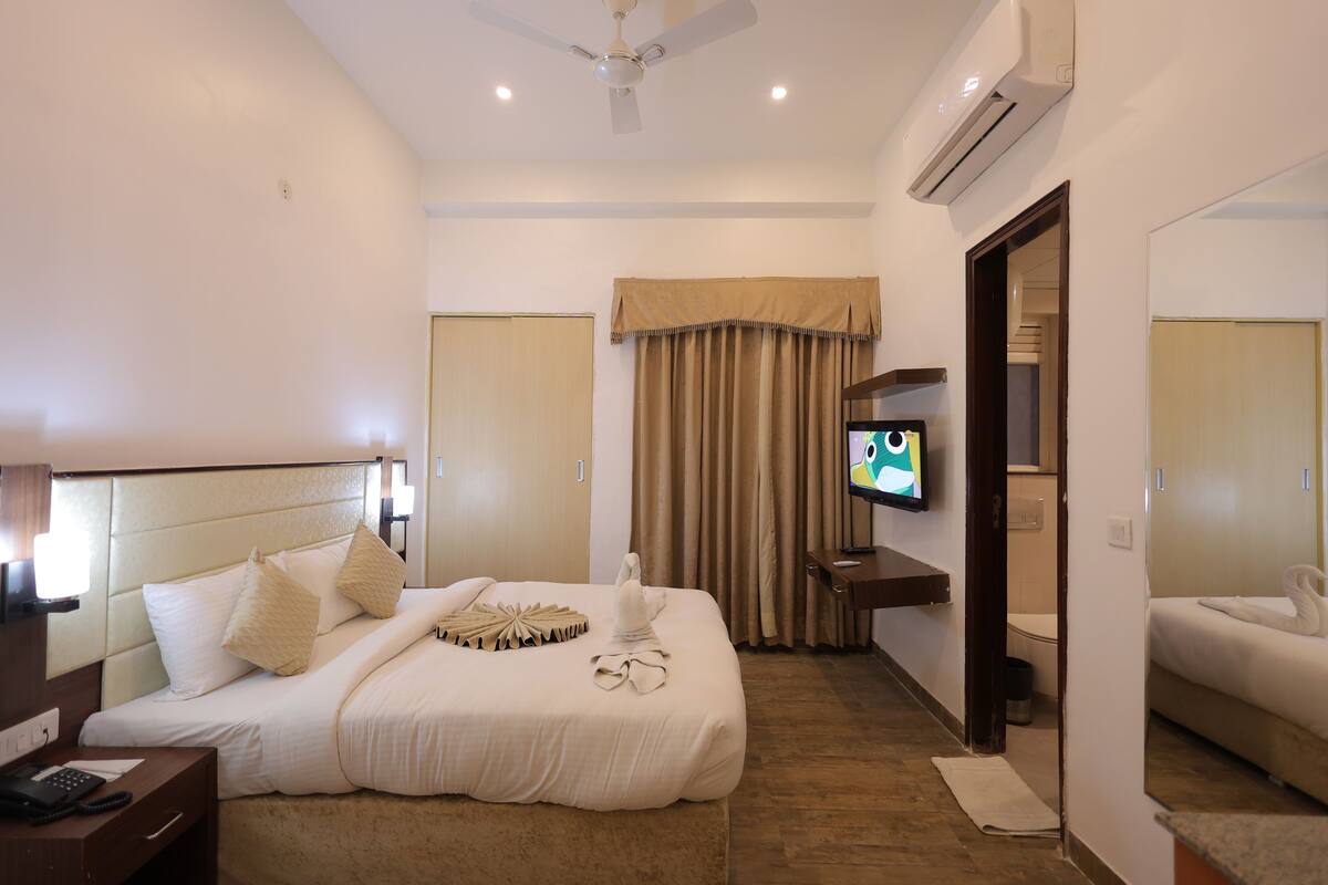 Une chambre d’hôtel équipée d’un lit, d’une télévision, d’un bureau avec un téléphone et d’un ventilateur de plafond.
