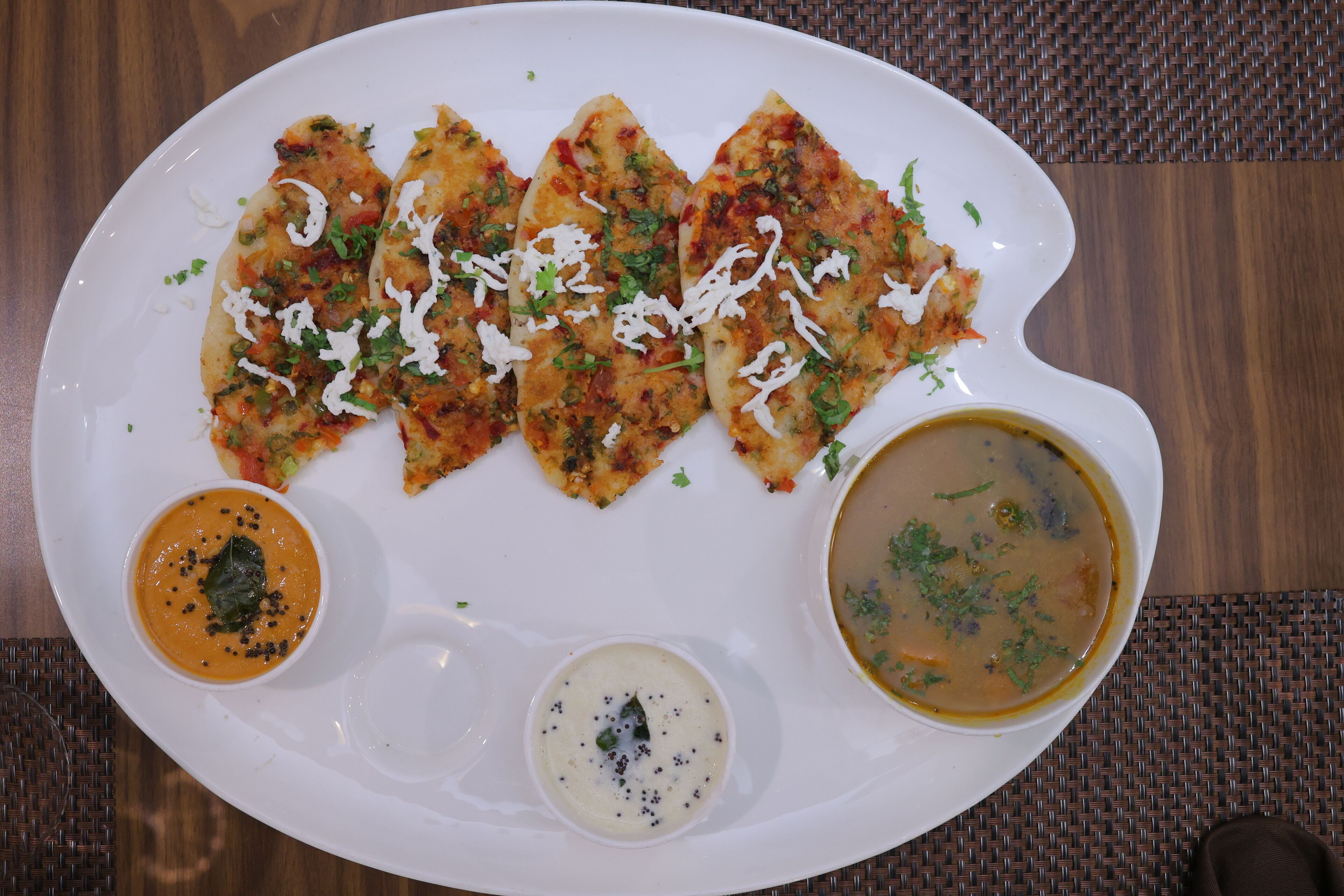 A white plate with three pieces of food, two dips, and a spoon.