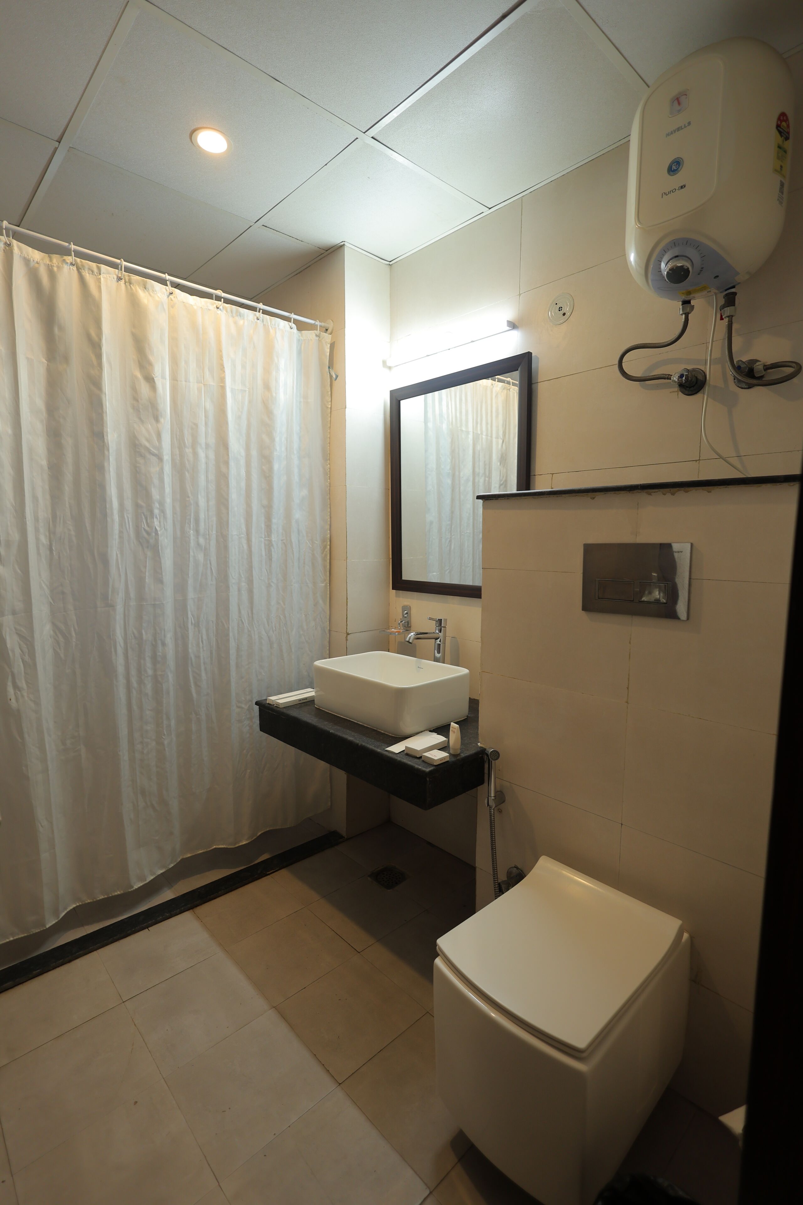 A bathroom with a shower curtain, a sink, a mirror, and a toilet.