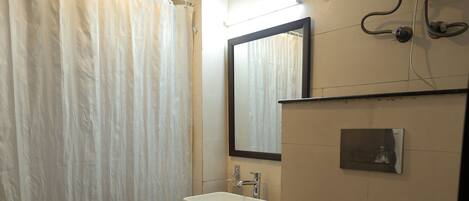 A bathroom with a shower curtain, a sink, a mirror, and a toilet.