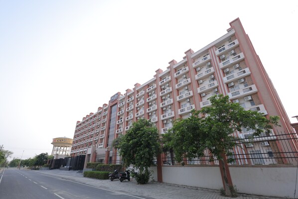 A multi-story residential building with balconies, a gated entrance, and a water tower in the background. - Hide Away Studios (Mathura)