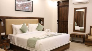 A neatly made bed with white linens and green pillows, a wooden headboard, and a bedside table with a lamp. - Four Seasons Resort (Adityapur)