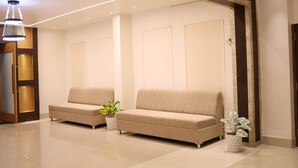 A modern waiting area with two sofas, a potted plant, and a ceiling light fixture. - Four Seasons Resort (Adityapur)