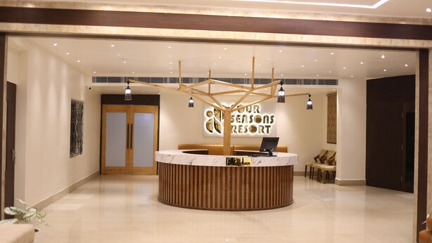 A reception area with a wooden reception desk, a digital screen, and a sign that reads "Your Seasons Resort". - Four Seasons Resort (Adityapur)