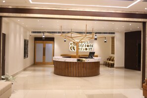 A reception area with a wooden reception desk, a digital screen, and a sign that reads "Your Seasons Resort". - Four Seasons Resort (Adityapur)