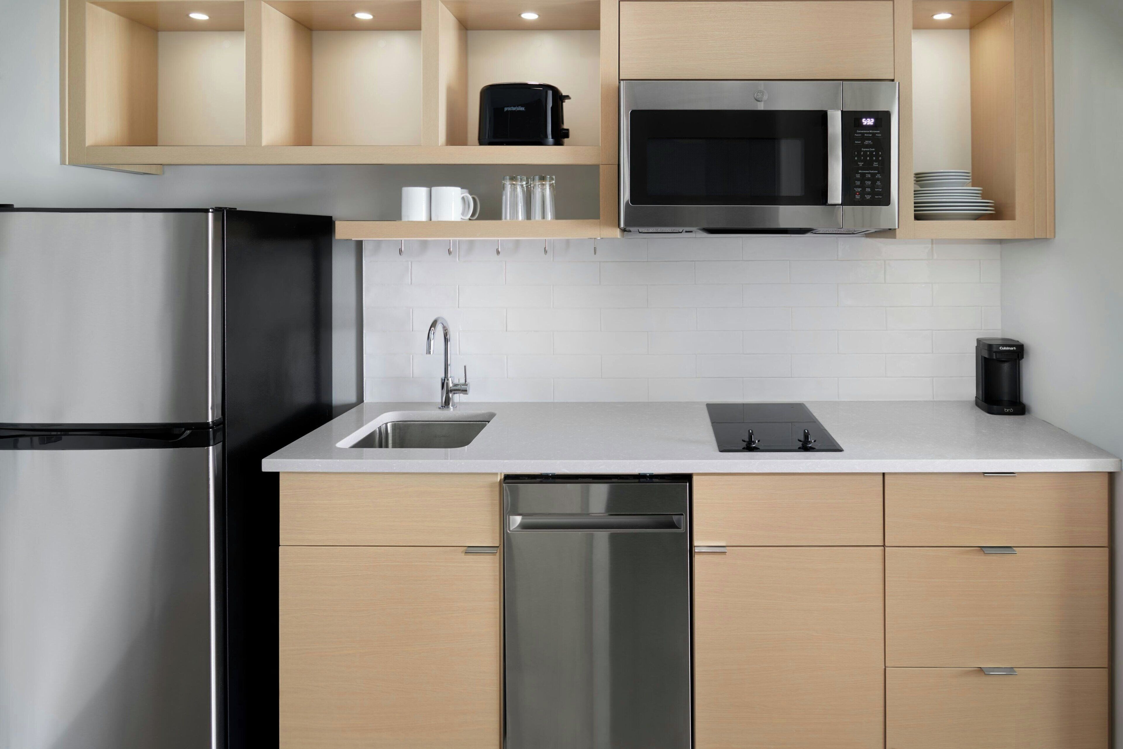 A modern kitchen with stainless steel appliances, wooden cabinets, and a white countertop.