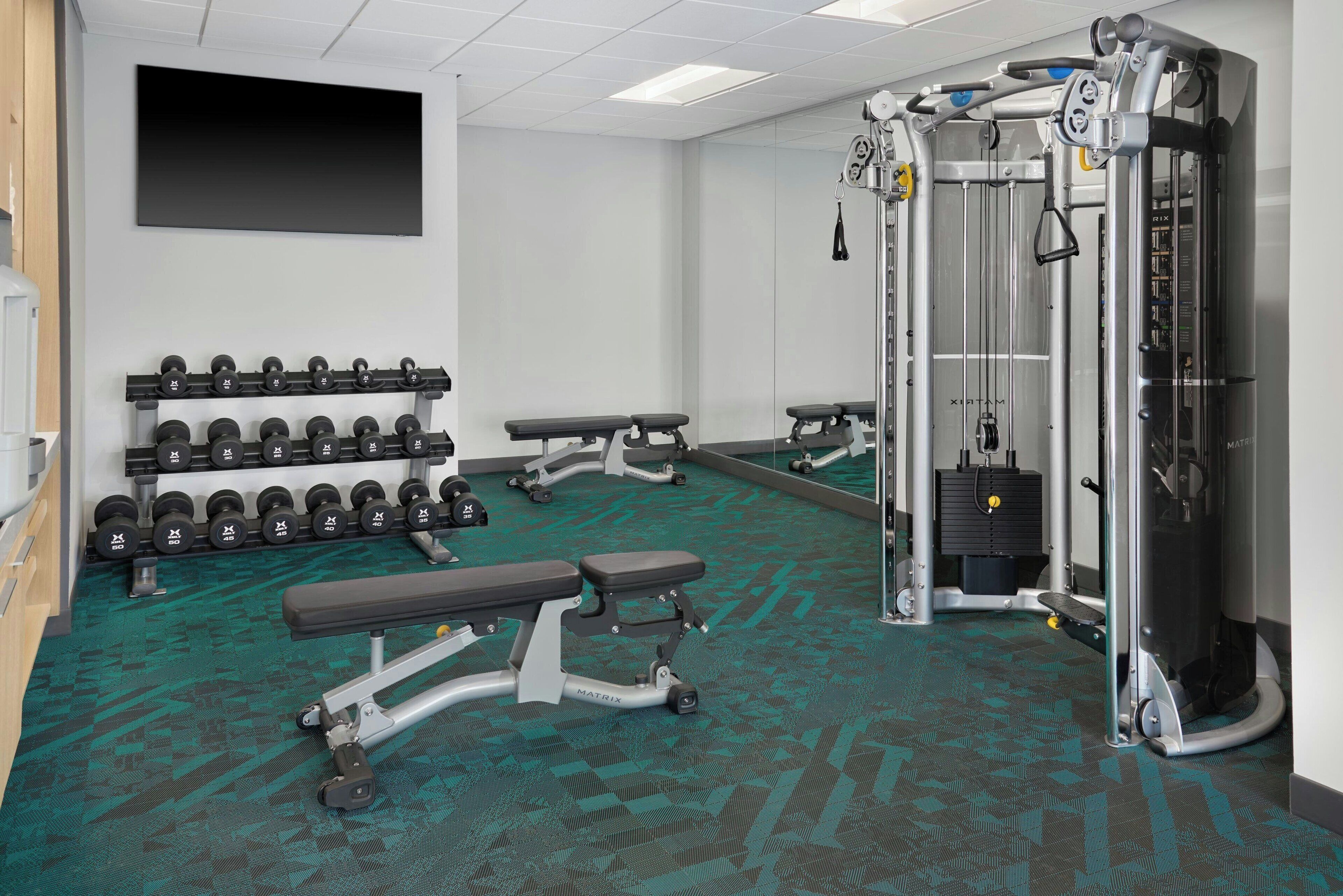 A gym with weightlifting equipment, benches, and dumbbells.
