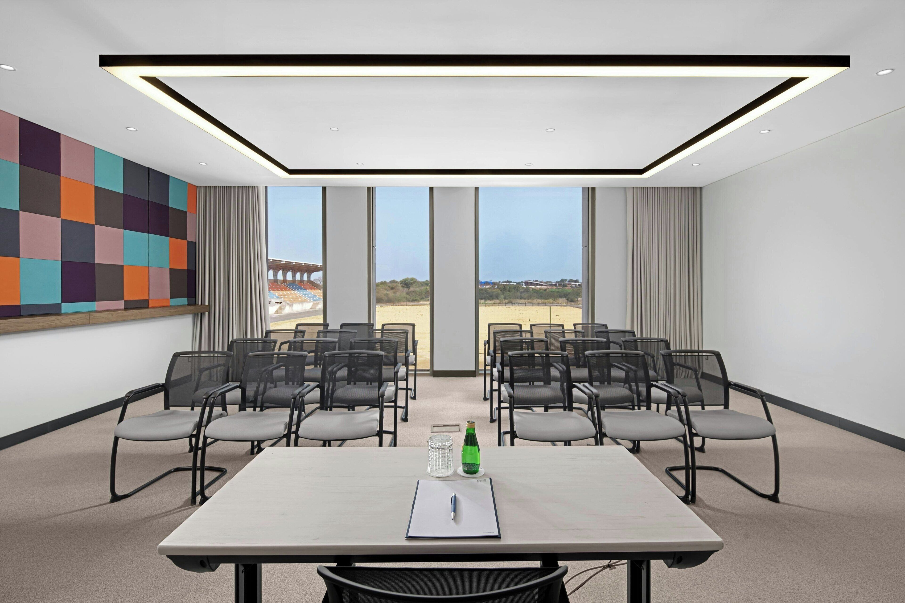 A conference room with a large table, chairs, and a view of a stadium.